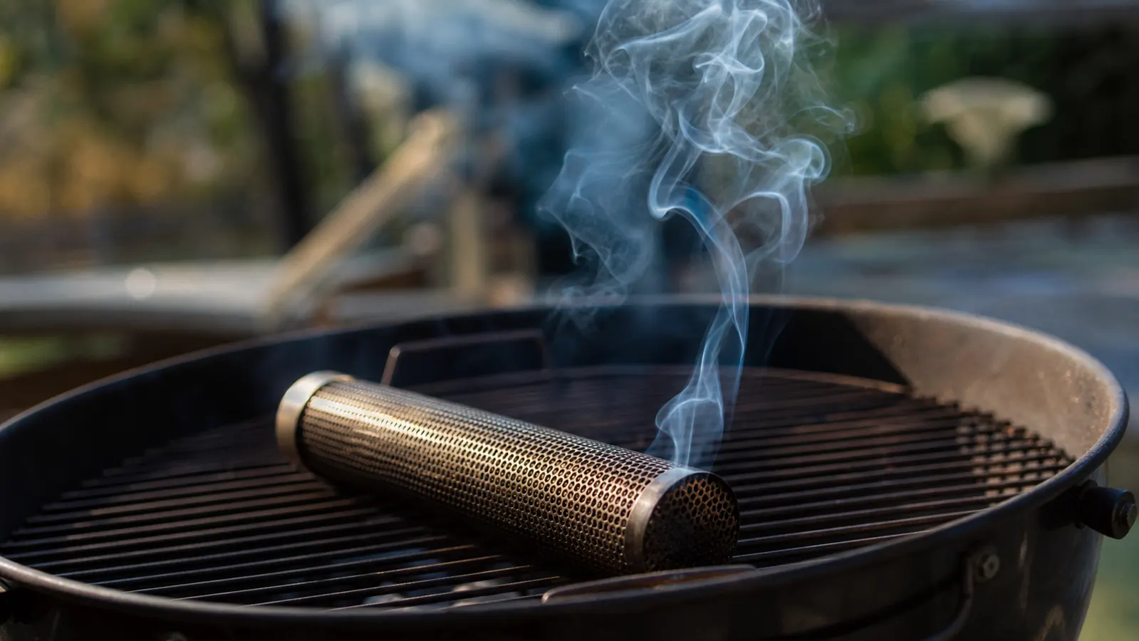 Thin blue smoke rising steadily from a pellet smoker tube on grill grates
